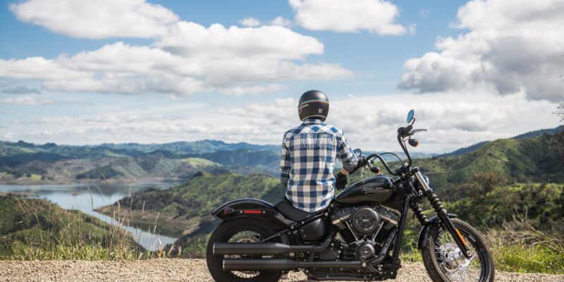 A man sits on a harley davidson motorcycle overlooking the mountains